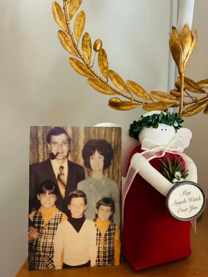 A 1970s family portrait postcard propped beside a ceramic angel with a gold laurel